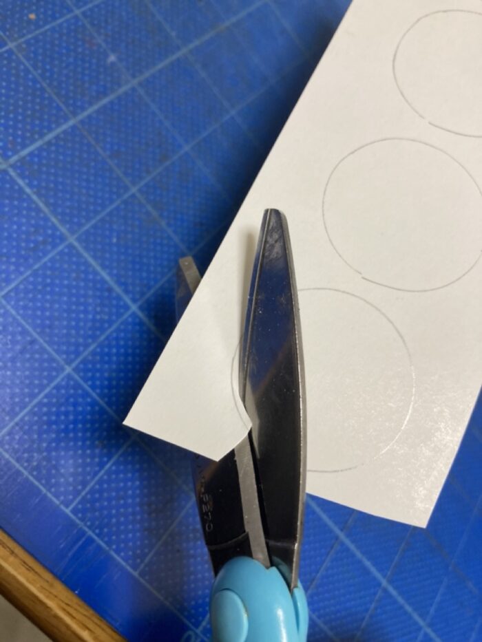 型取った紙をハサミで丸く切り取る手元
